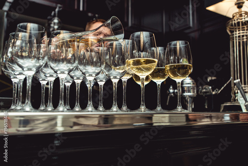 bartender pouring white wine into glass at wine tasting