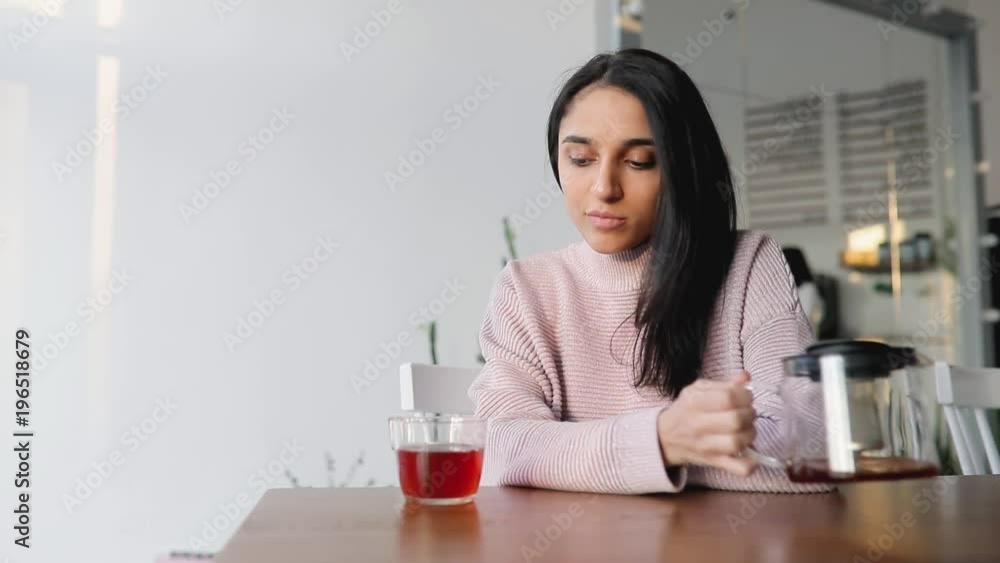 Beautiful woman pouring tea into glass in a cafe Beautiful woman pouring tea into glass in a cafe