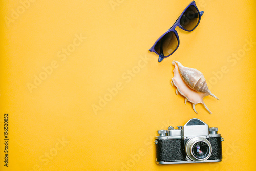 Accessories a traveler on a yellow background with sunglasses, shell and a camera.Top view travel or vacation concept. Summer background. photo