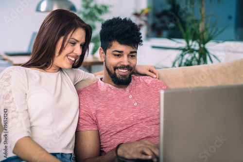 Happy couple with laptop spending time together at home