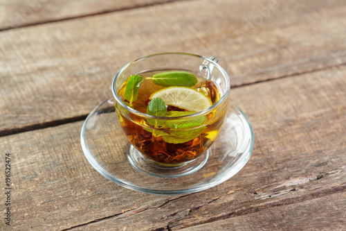 cup of black tea with mint leaves on a wooden table