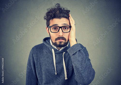 Portrait of disappointed stressed bearded young man on a gray background. Negative human emotions photo