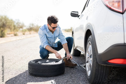 фотографія Man replacing the flat tire on the car