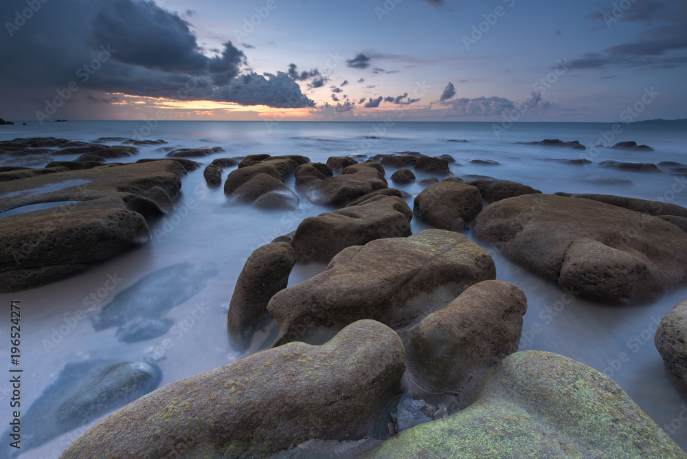 Sunset Seascape with unique rock formation covered by green moss.