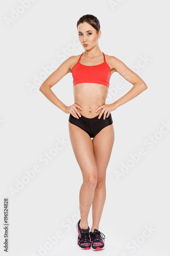 Slender girl in sports clothes posing, holding hands on waist