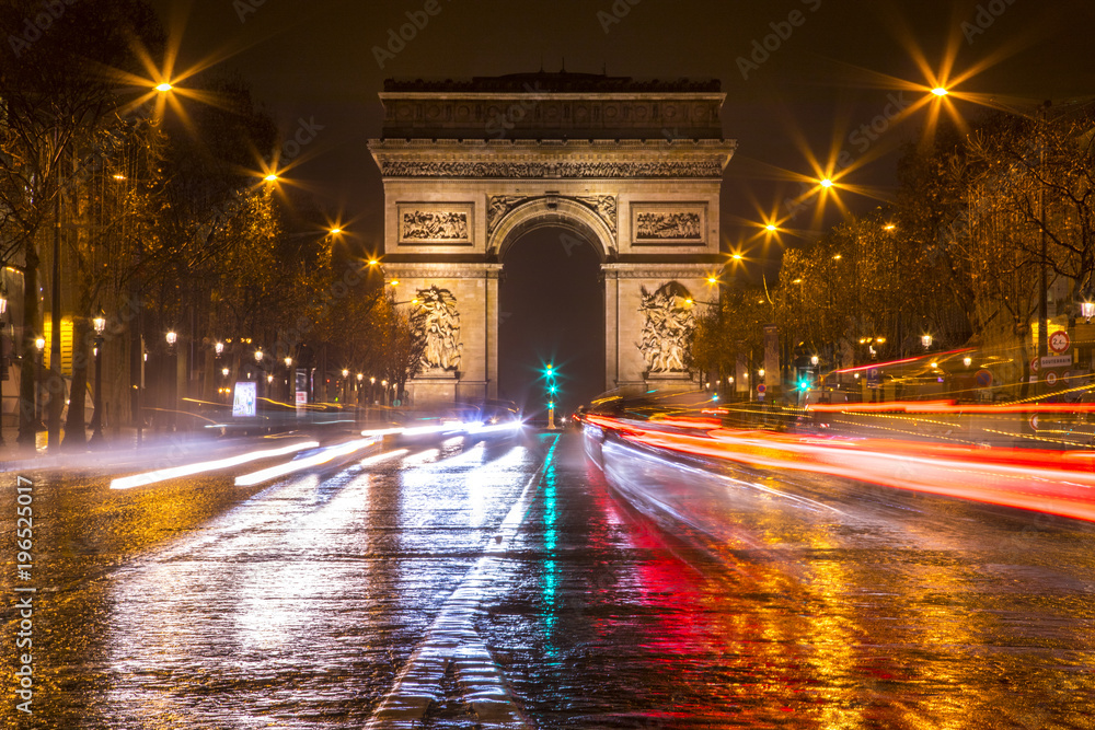 Long exposure shot of traffic racing down the Champs Elysees in Paris, France around the Arc de Triomphe