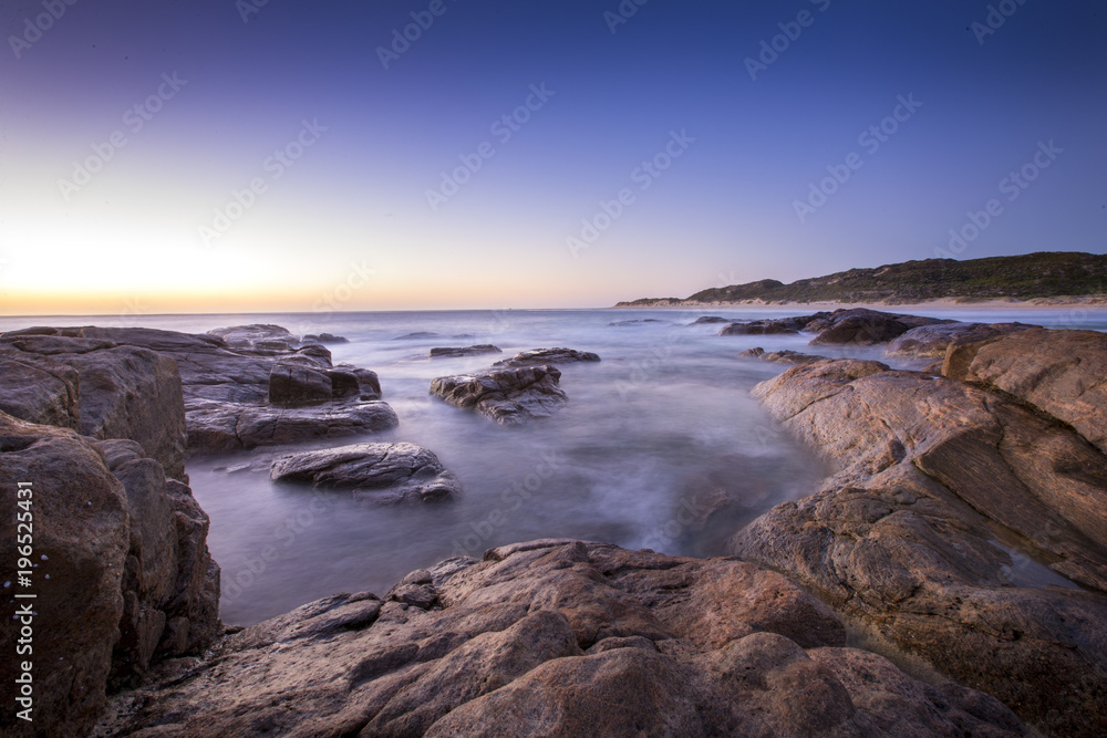 Long exposure of waves rushing over the rocks just after sunset at Surfers Point near Margaret River in Western Australia.