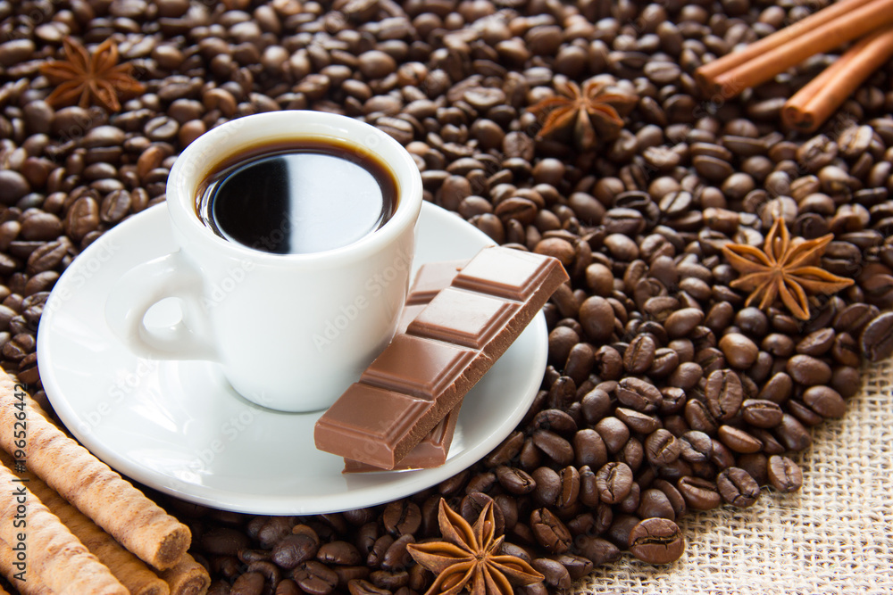 fried coffee beans with a cup on a saucer with an espresso drink with cinnamon and anise and milk chocolate fried coffee beans with a cup on a saucer with an espresso drink with cinnamon and anise and milk chocolate