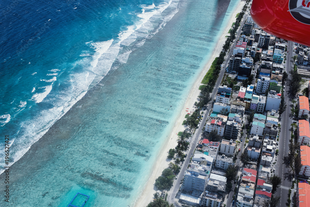 Aerial view of tropical Maldive City buildings and beach from seaplane
