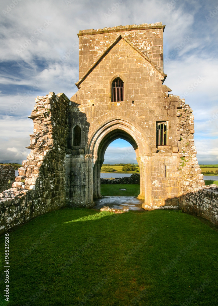 Ruins of Oratory of Saint Molaise abbey on Devenish Island with green lawn in foreground. Enniskillen, Northern Ireland