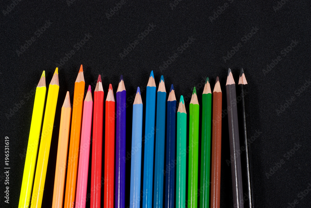 Business concepts: colourful pencils in the hand on black background Business concepts: colourful pencils in the hand on black background