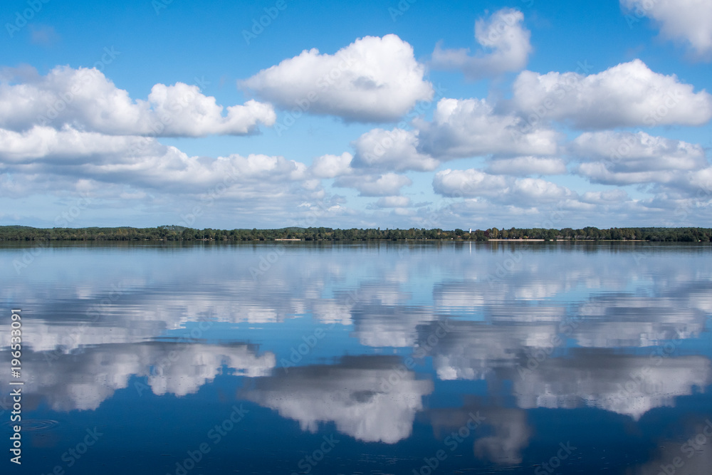 Wolken am blauen Himmel mit Spiegelbild im Wasser