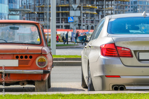 Rear view of two cars of different eras standing side by side in the city. The concept of technology development