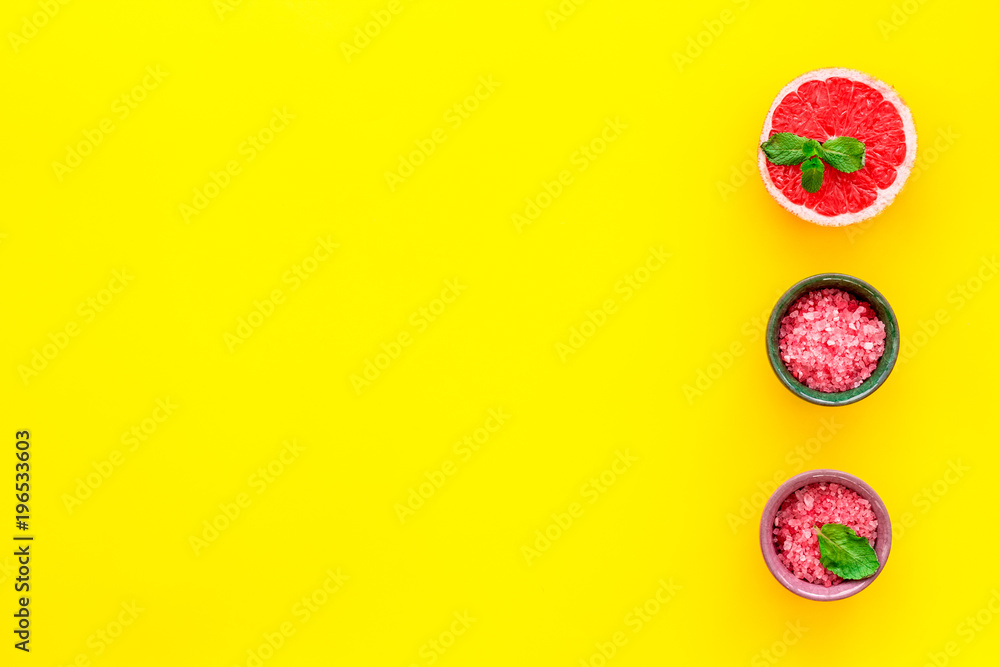Natural citrus cosmetics. Spa salt near grapefruit on yellow background top view mockup