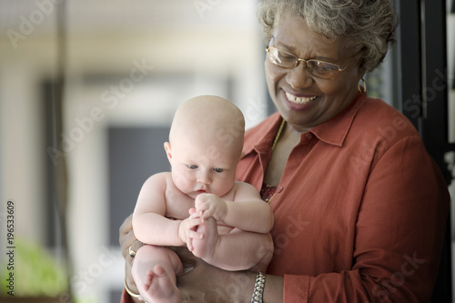 Baby being held by a mature adult woman.