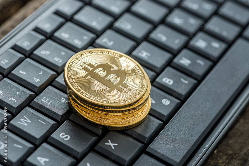 High angle view of four golden bitcoins on a keyboard High angle view of four golden bitcoins on a keyboard