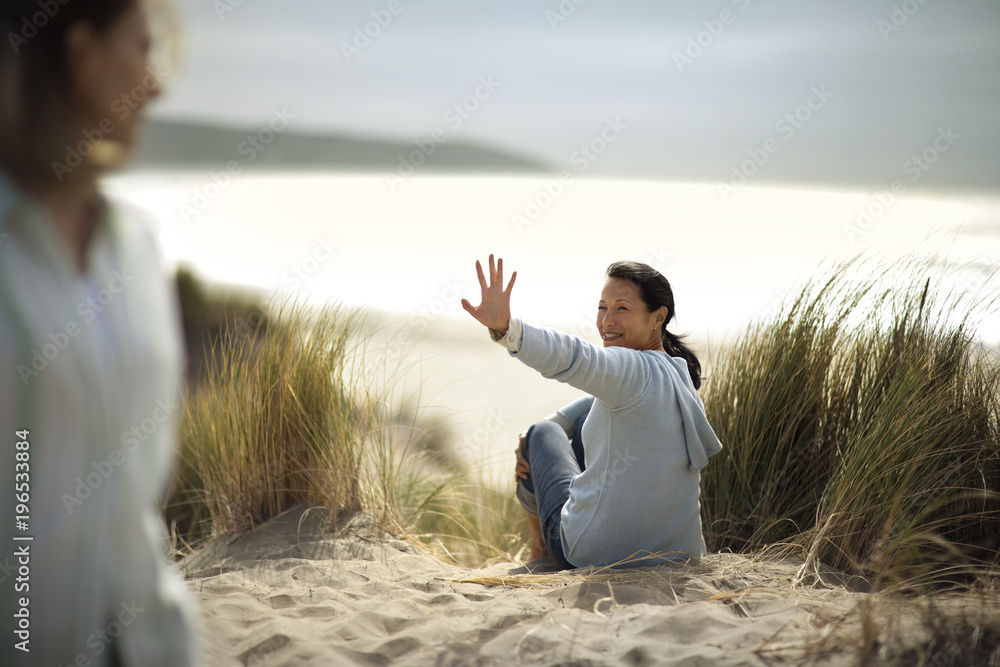 Woman waving goodbye to her friend at the beach. Woman waving goodbye to her friend at the beach.