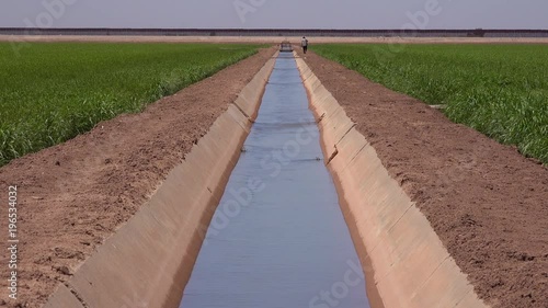 A farmer walks along the US Mexico border with the wall in the background.