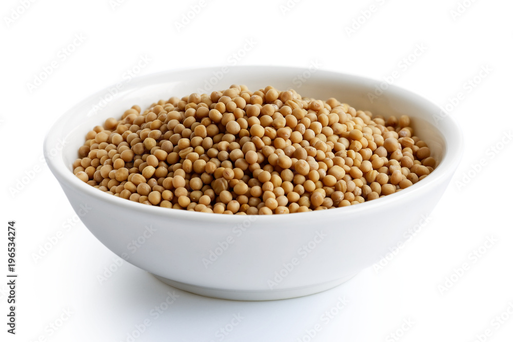 Dried white mustard seeds in white ceramic bowl isolated on white.