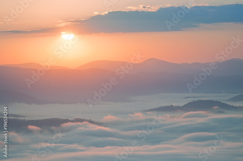 Sunrise over clouds of fog in the mountains.