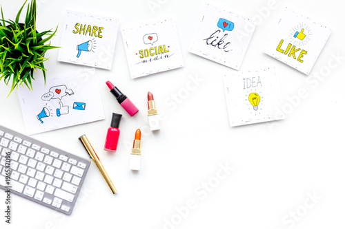 Beauty blogger workplace concept. Keyboard, cosmetics, social media icons on white desk top view space for text