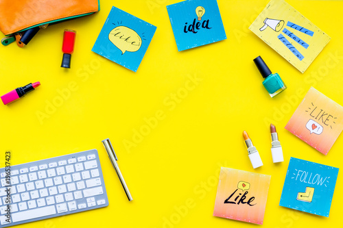 Female blogger concept. Work desk with keyboard, cosmetics and social media icons on yellow desk top view space for text