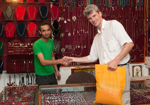 Φωτογραφία Store salesman in India sells goods to a tourist and bargain