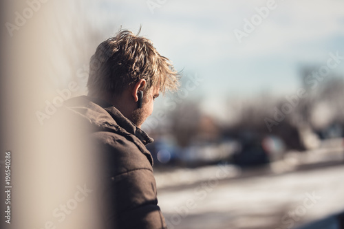 Young guy using hands free technology on mobile device for communication headset. Talking business on bluetooth handsfree outside.