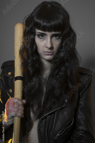 Alone, Juvenile delinquency concept, young brunette teenager with black leather jacket and jeans with a baseball bat photo