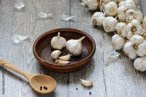 garlic in a clay plate with a wooden spoon on the table