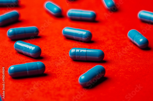 Blue pills capsule on red background Medicine and pharmacy concept.