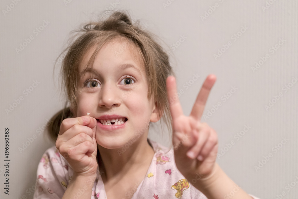 A little girl had a milk tooth. She holds it in her hand A little girl had a milk tooth. She holds it in her hand