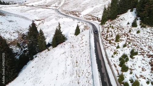 Aerial tracking shot of a car on a mountain road during winter photo