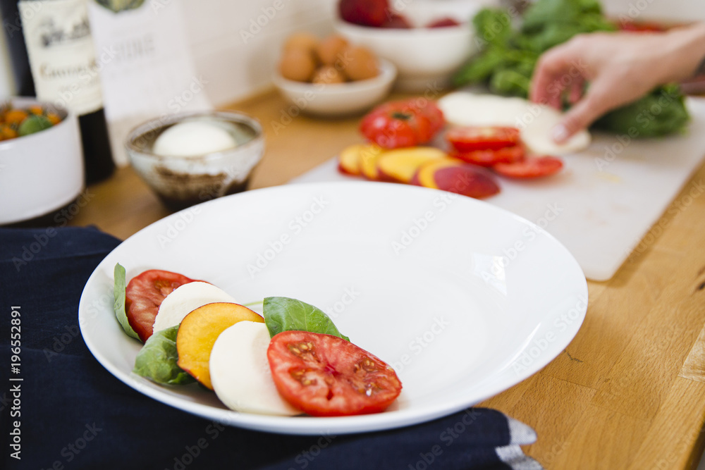 A caprese salad being assembled in a kitchen A caprese salad being assembled in a kitchen
