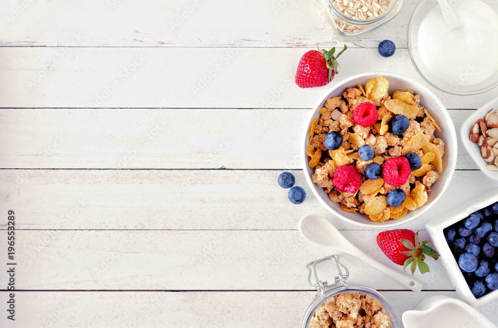 Cereal and ingredients for a healthy breakfast forming a side border over a white wood background. Top view. Copy space. - obrazy, fototapety, plakaty 