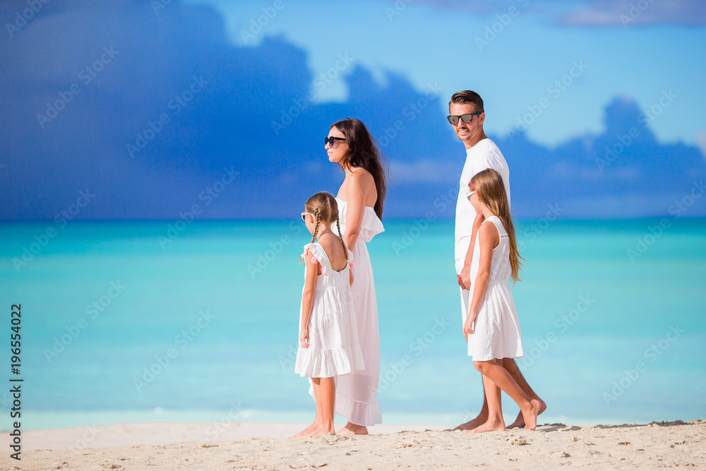 Family of four walking on white tropical caribbean beach Family of four walking on white tropical caribbean beach