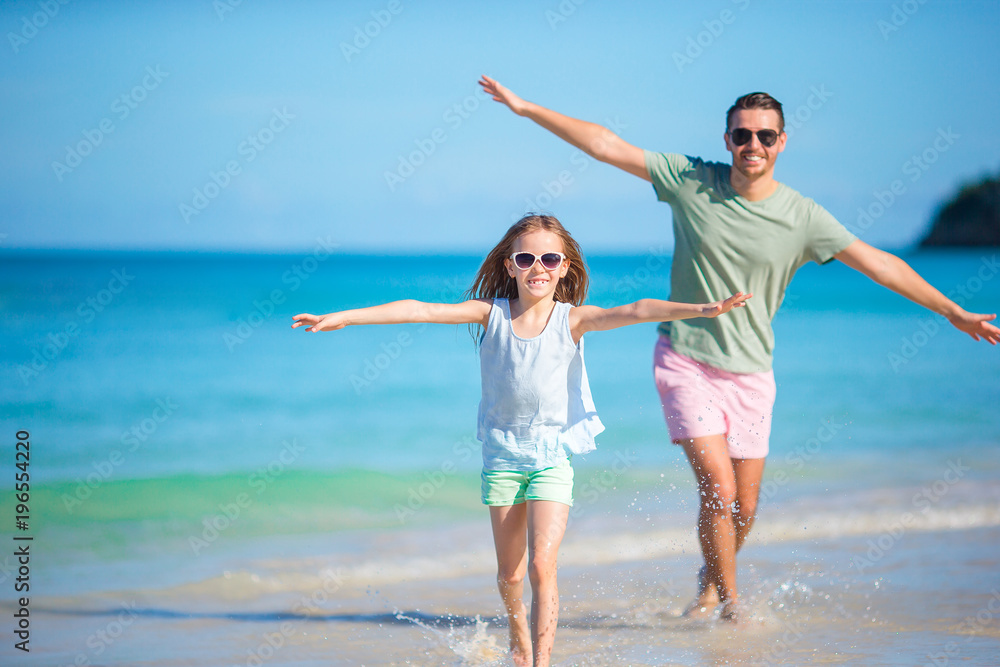 Little girl and happy dad having fun during beach vacation Little girl and happy dad having fun during beach vacation
