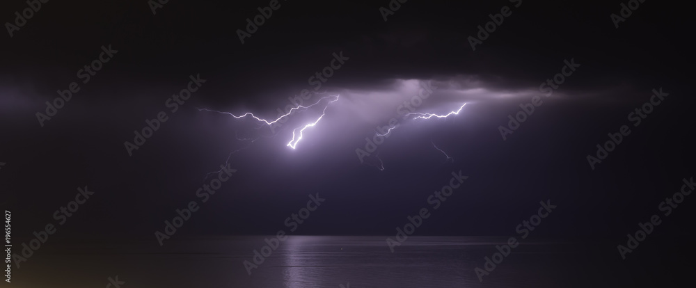 lightning bolts reflection over the sea. taken during a thunderstorm over the ocean with clouds in the background