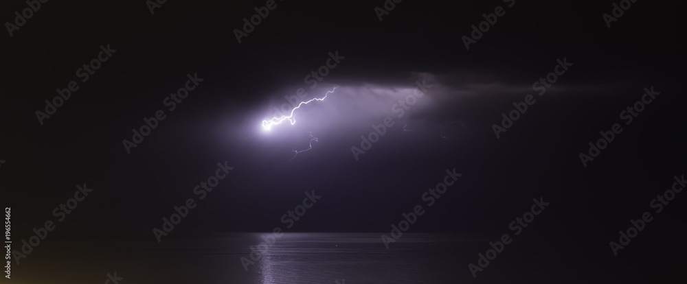 lightning bolts reflection over the sea. taken during a thunderstorm over the ocean with clouds in the background