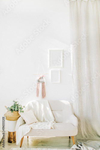 Interior design concept. Bright room with white walls, eucalyptus in straw basket, chair and curtains.