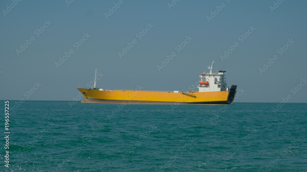 yellow cargo ship at sea on a summer day