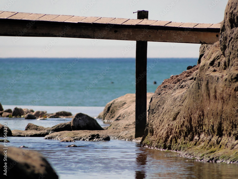 Río desembocando en el mar. Acantilado. Puente peatonal. Río desembocando en el mar. Acantilado. Puente peatonal.
