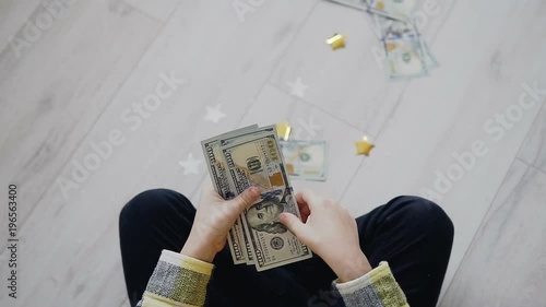 Top view of children hands holding dollars and counting them by throwing them on the floor at home. American currency photo