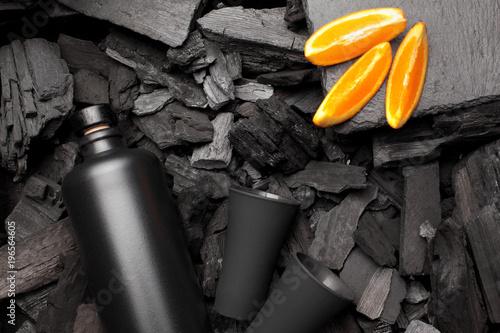 Original black matte bottle of vodka or tequila and shot glass .Slices of oranges.On charcoal background. Black edition.Creative.Let's drink.Cheers.Copy space photo