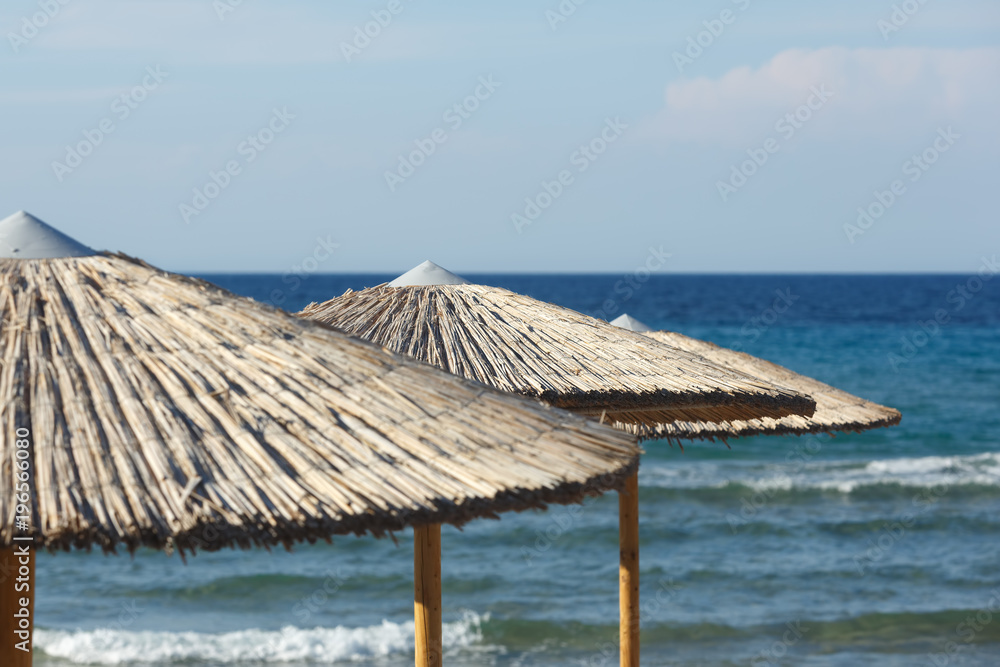 Straw umbrellas on sea background Straw umbrellas on sea background