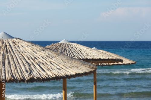 Fototapeta Naklejka Na Ścianę i Meble -  Straw umbrellas on sea background
