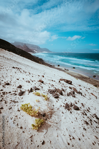 Remote deserted beach Praia Grande. Spectacular sand dunes, ocean waves and black volcanic stones. Barren vegetaion of Calhau, Sao Vicente Island Cape Verde photo