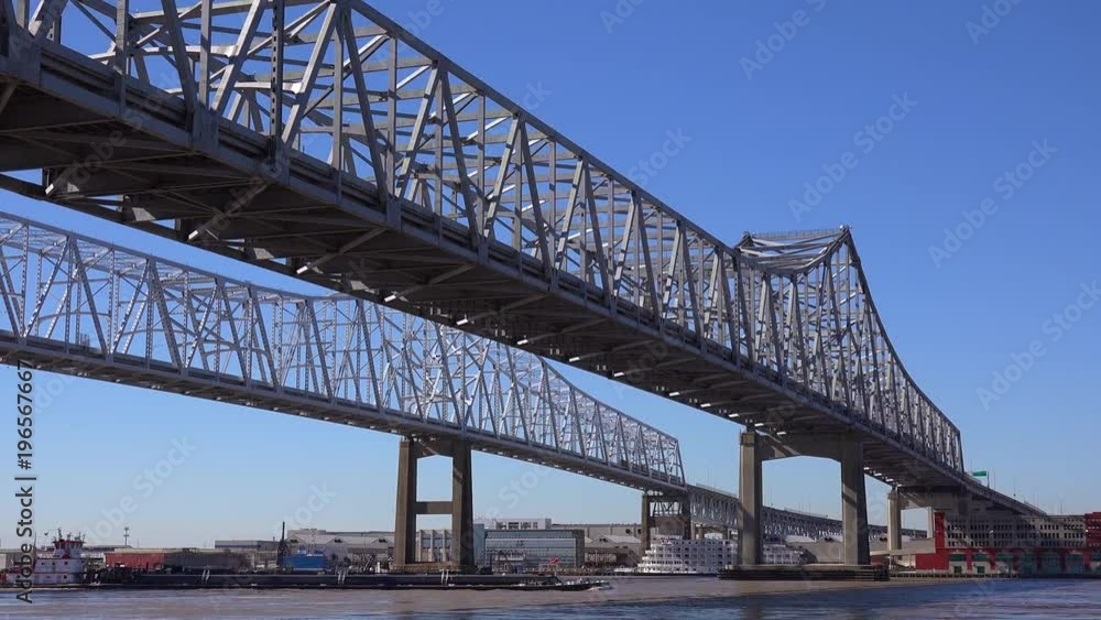 Cargo ships and other boats travel under the Crescent City Bridge with New Orleans Louisiana in the background. Cargo ships and other boats travel under the Crescent City Bridge with New Orleans Louisiana in the background.