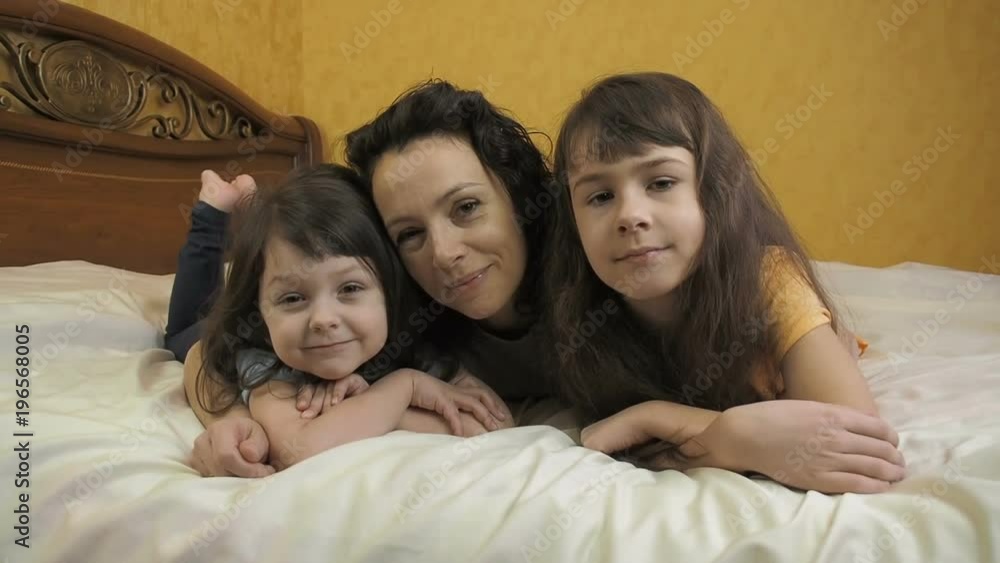 Woman with children in the bedroom. Mom and daughter lie on the bed. Woman with children in the bedroom. Mom and daughter lie on the bed.