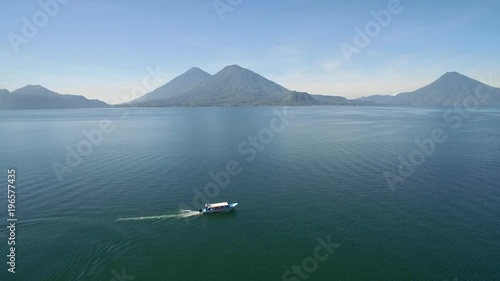 Aerial over a boat on Lake Amatitlan in Guatemala reveals the Pacaya Volcano in the distance. photo